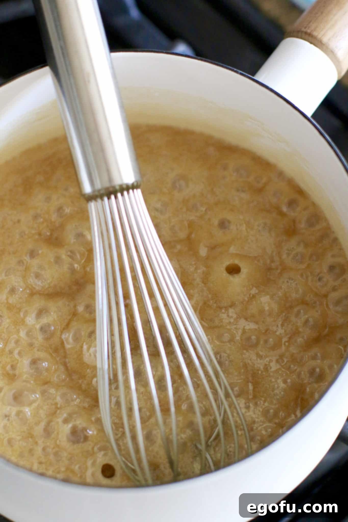 caramel glaze shown in a white pot and a whisk. 