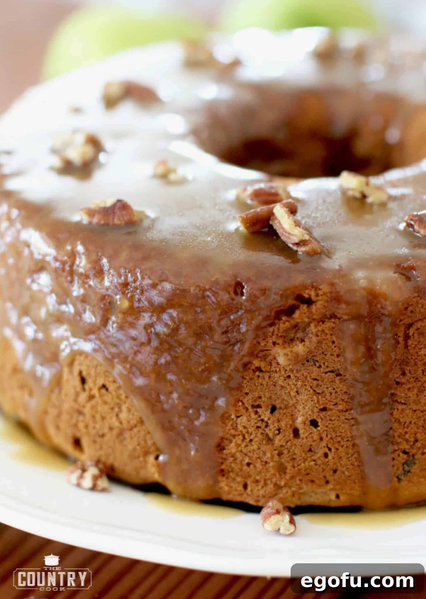 Homemade Caramel Apple Cake shown fully baked and glazed on a large white serving platter. 