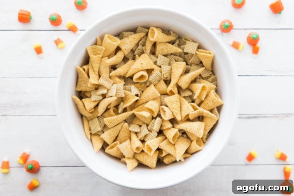 Chex cereal and Bugles in a large white bowl, ready for the sweet glaze.