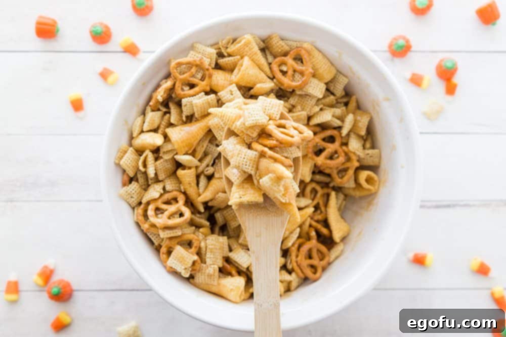 Sweet brown sugar sauce on chex mix with a wooden spoon holding up some of the mix, showing the even coating.