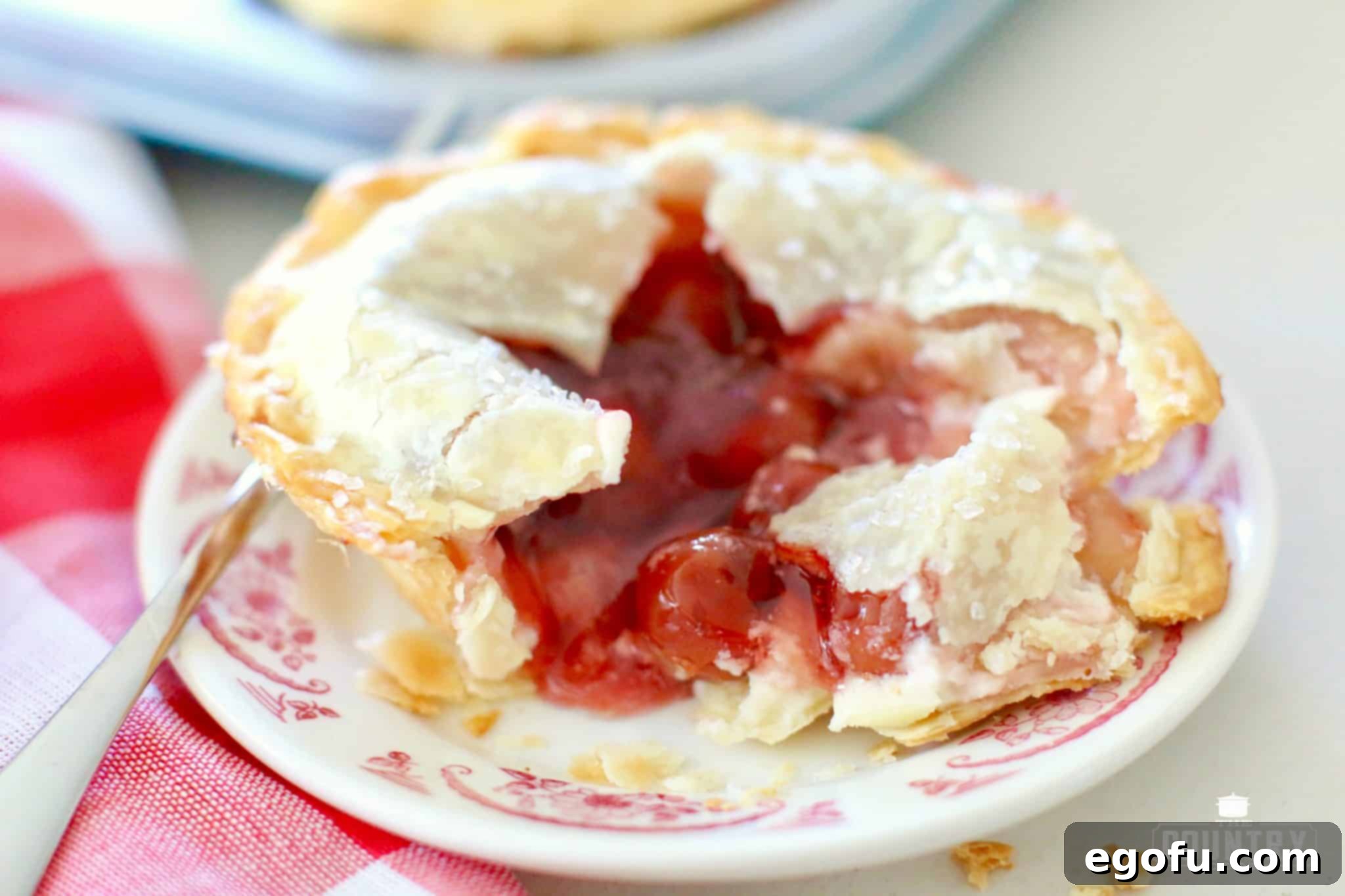 Cherry Cheesecake Minis 2 Cherry Cheesecake Mini Pies - a top-down view of several beautifully baked mini pies on a baking sheet, showcasing their golden-brown crusts and sugared tops.