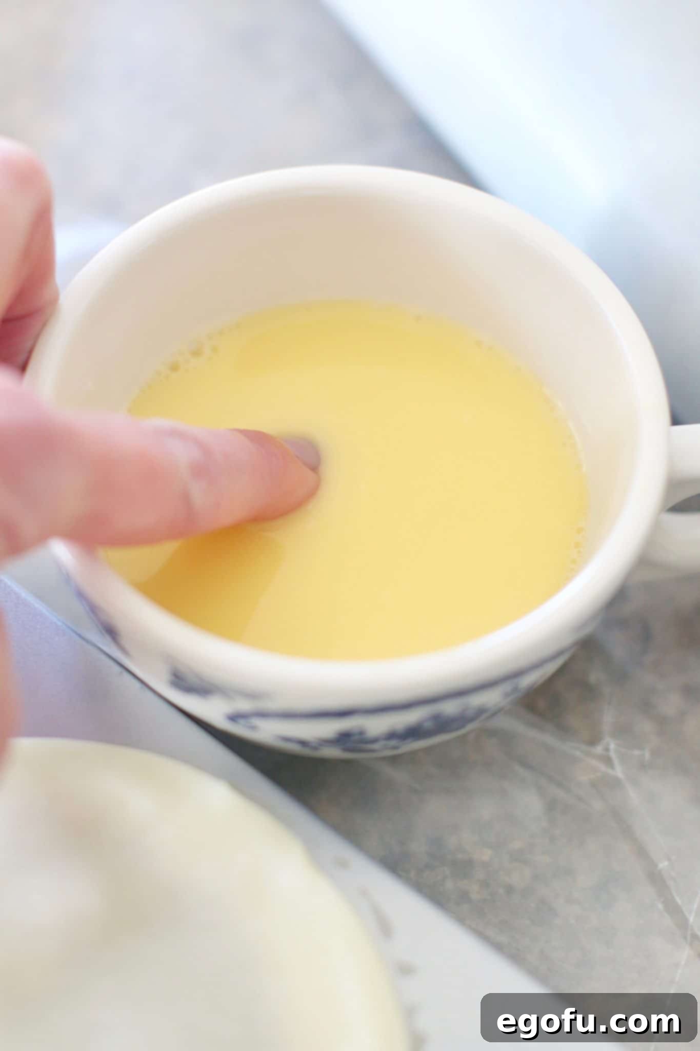 Cherry Cheesecake Minis 11 A small bowl of egg wash, a mixture of beaten egg and water, whisked to a pale yellow consistency, ready for application.