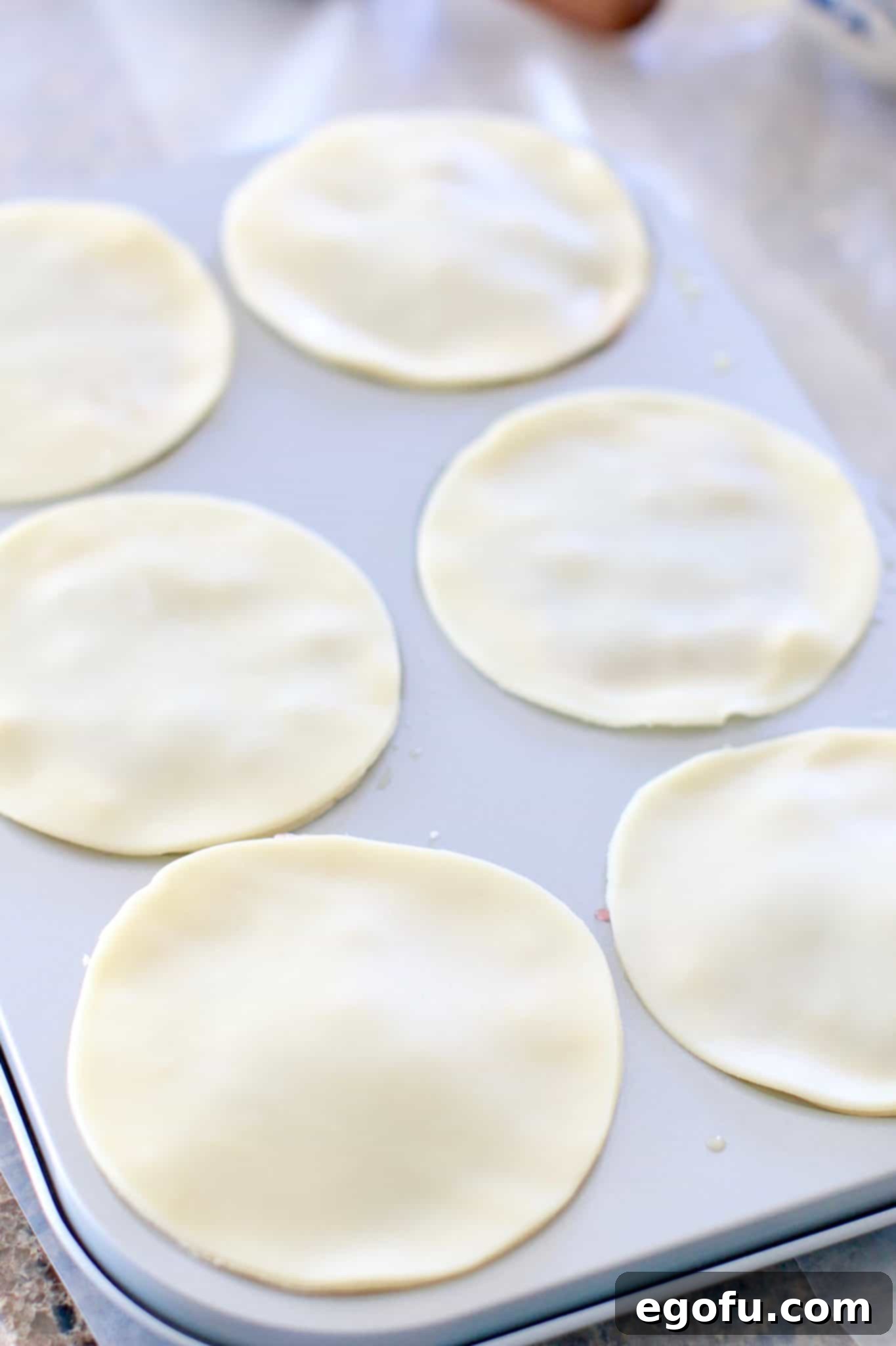 Cherry Cheesecake Minis 13 Smaller pie crust topping circles carefully placed over the filled mini cherry cheesecakes in the mini pie pan, ready for sealing.