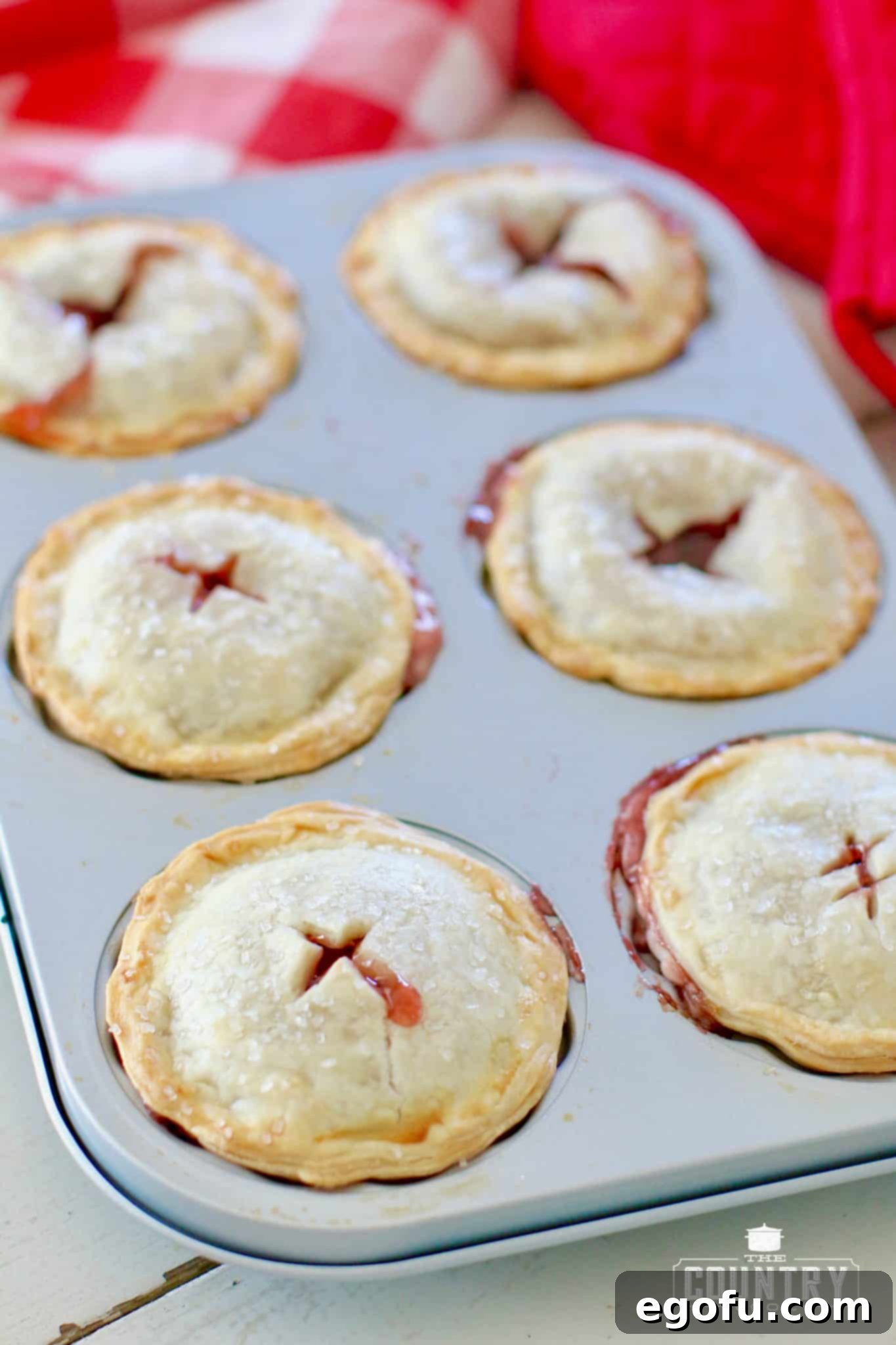 Cherry Cheesecake Minis 17 A batch of freshly baked mini cherry cheesecake pies, golden brown and perfectly puffed, cooling on a rack.