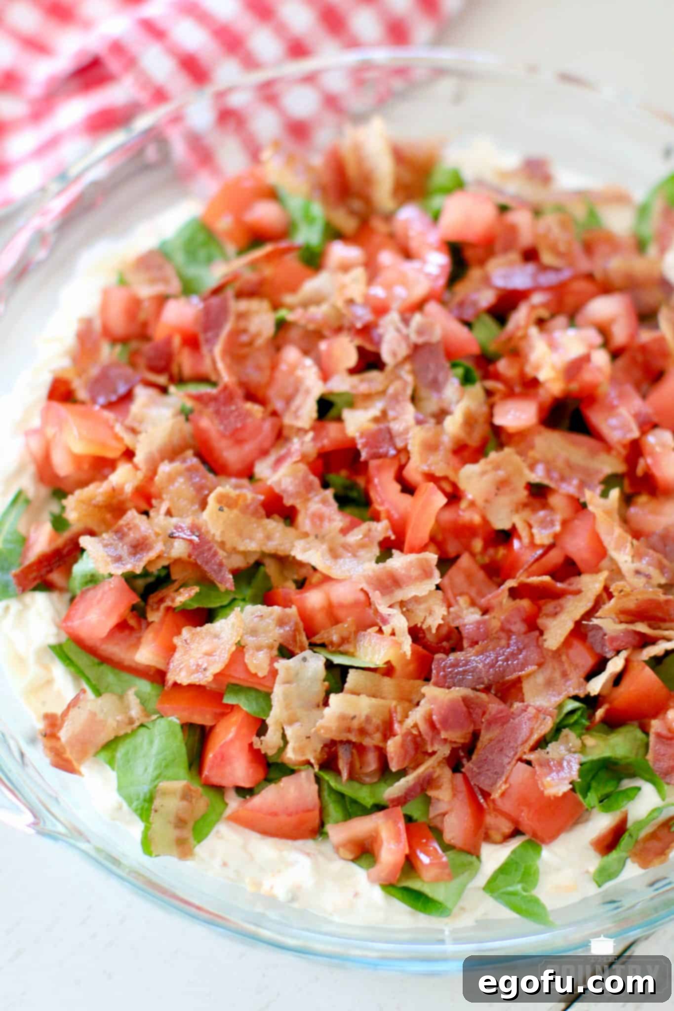 Lettuce, Tomatoes and Bacon on Veggie Cream Cheese Dip in a clear pie dish.