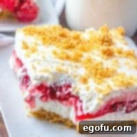 A perfectly portioned slice of No-Bake Cherry Yum Yum dessert on a plate, ready to be enjoyed, with a blurred background.