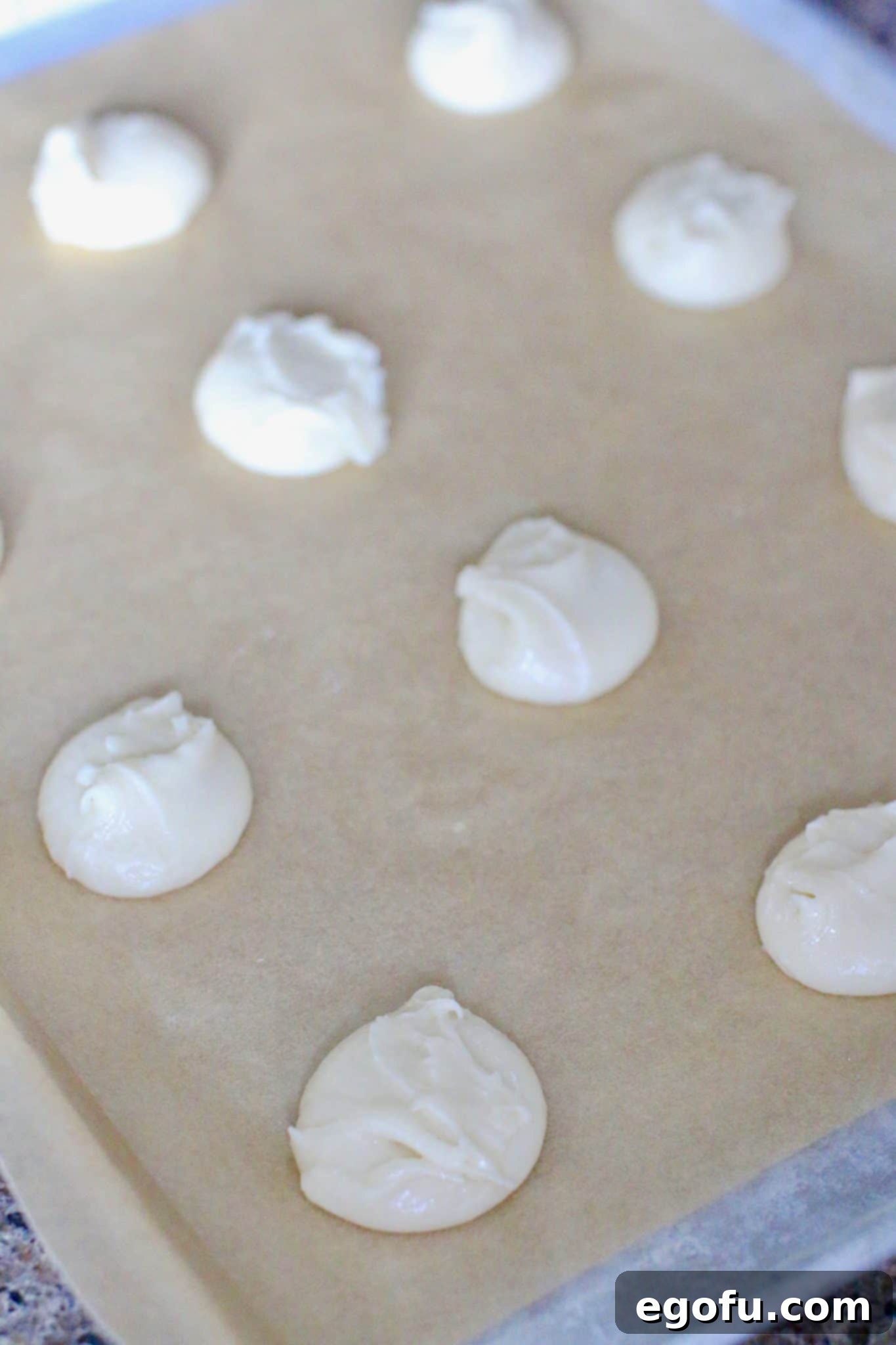 Cookie dough dropped onto a parchment-lined baking sheet, spaced for baking.