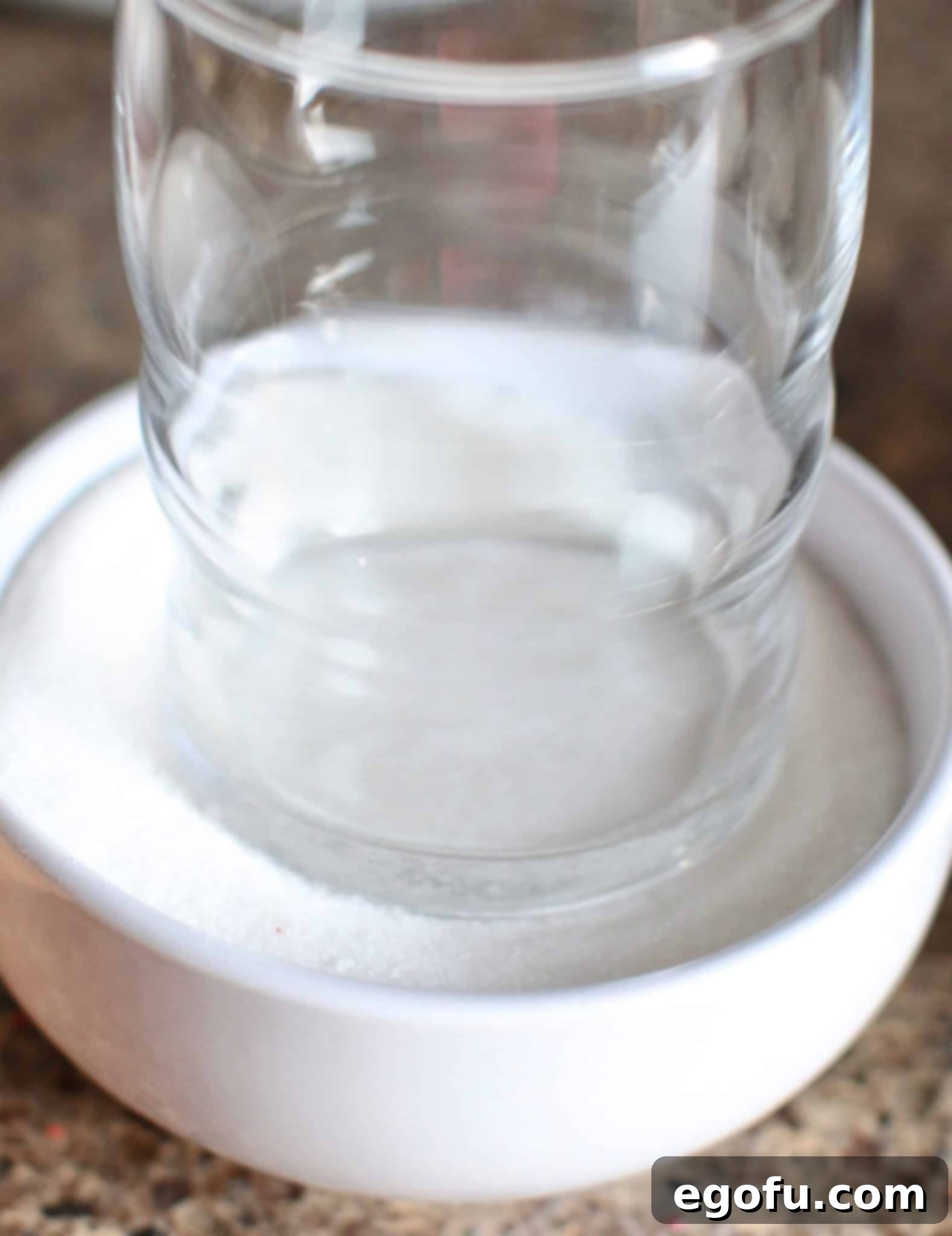 Bottom of a small glass dipped in colored sugar, ready to press onto cookie dough.