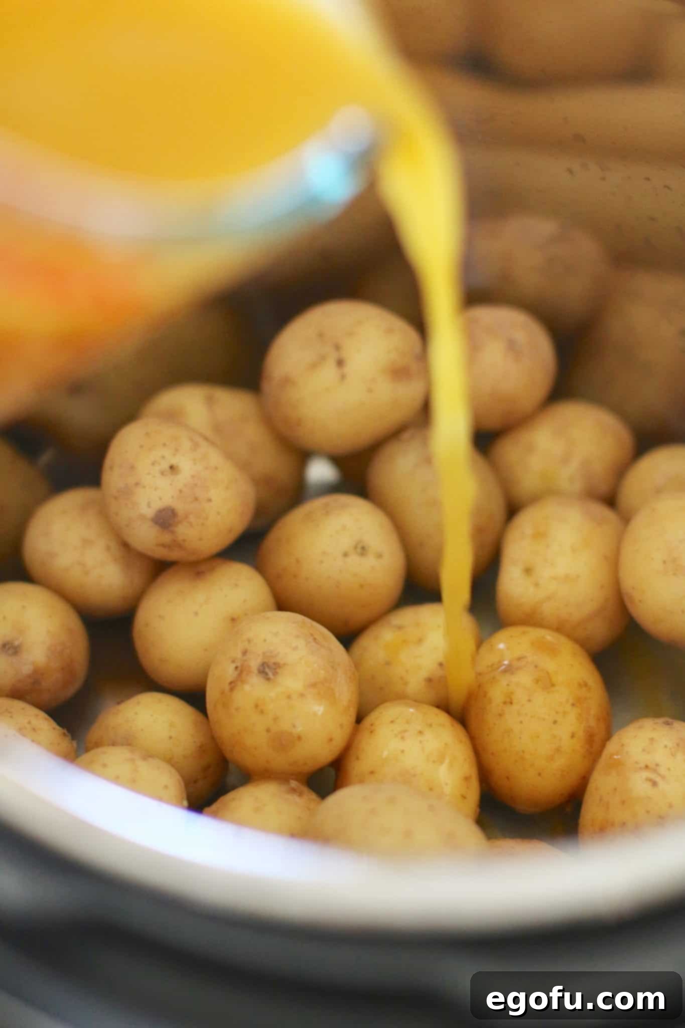 Chicken broth and minced garlic poured over new potatoes in the Instant Pot, forming the flavorful liquid base.