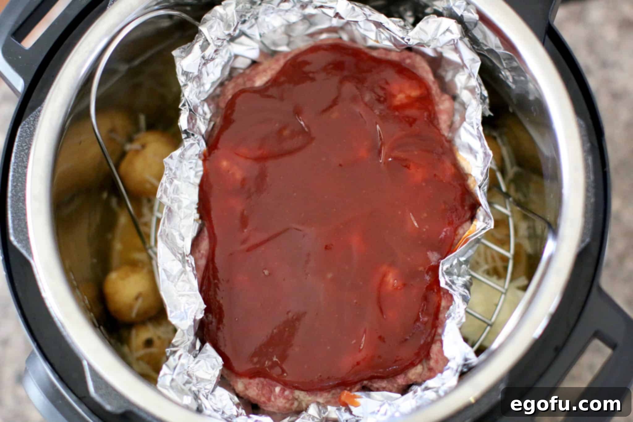 The prepared meatloaf on its rack insert, nestled above the potatoes in the Instant Pot, ready for pressure cooking.