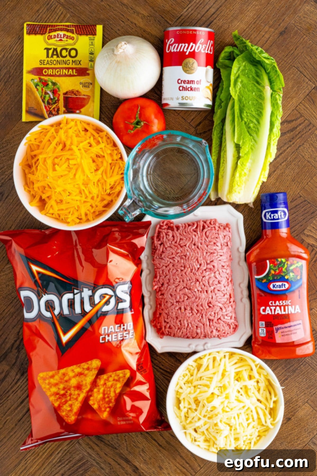 Ground beef, onion, taco seasoning, Doritos, lettuce, Catalina dressing, shredded cheese, tomato, and Cream of chicken soup.