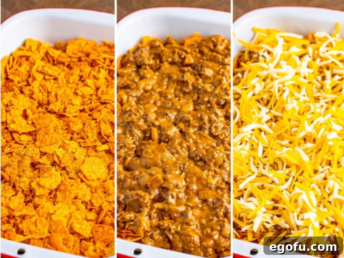 A baking dish with a layer of crushed Doritos, another with beef and onion on top and a final with shredded cheese on top.