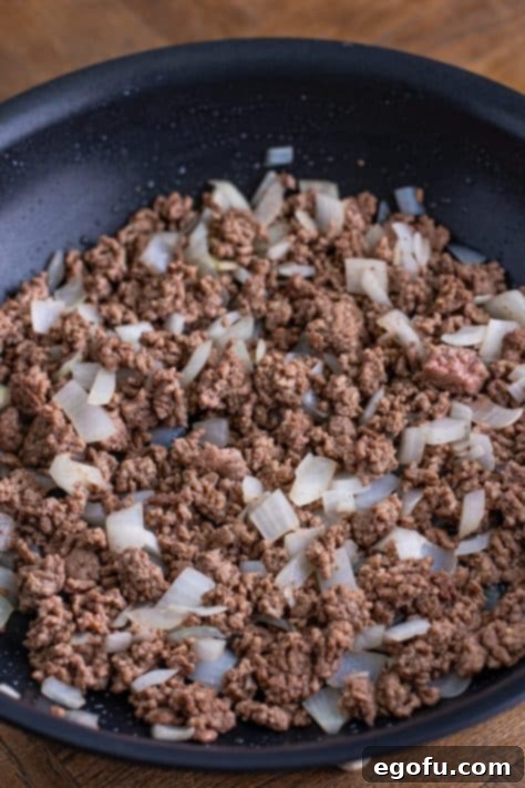 Ground beef and onion in a skillet.
