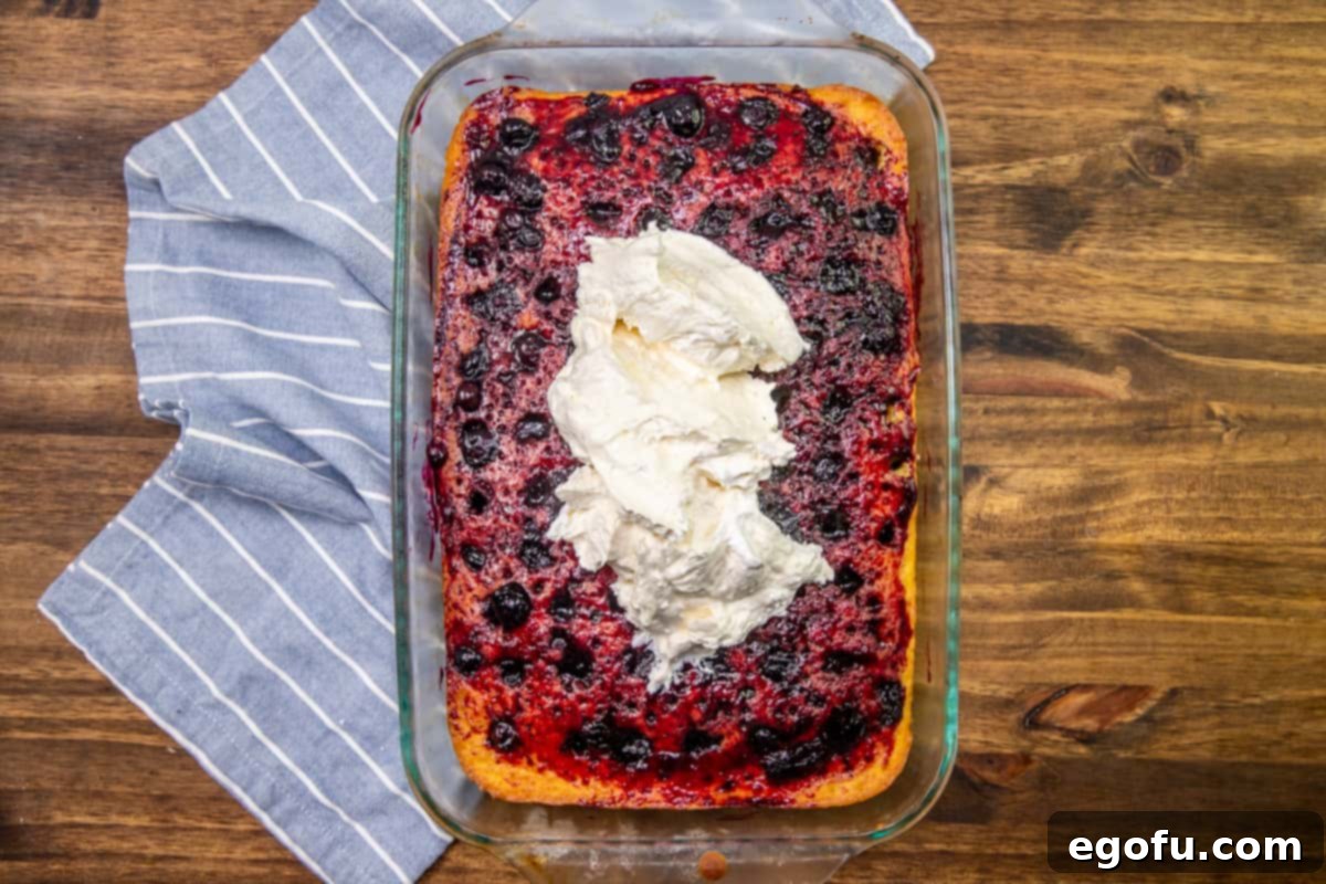 spread lemon curd frosting onto blueberry lemon cake.