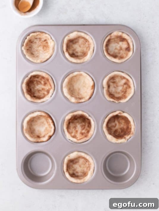 Biscuit dough pressed into muffin tin cups.