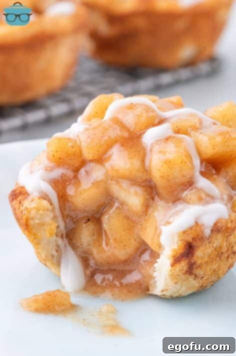A freshly made Apple Pie Cinnamon Roll with a bite taken, revealing the warm apple filling.