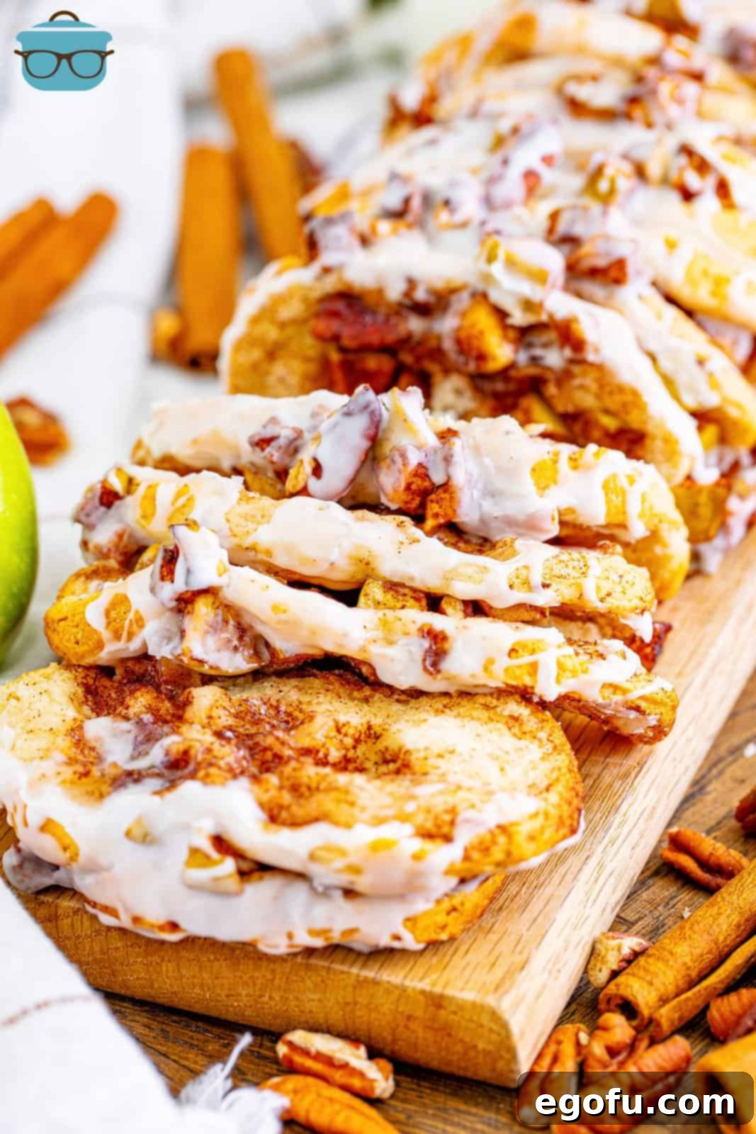 Slices of freshly baked Cinnamon Apple Pull-Apart Bread arranged on a rustic wooden board, showcasing the golden-brown crust and juicy apple filling.