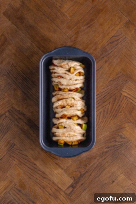 Stacked biscuit slices arranged neatly in a loaf pan, ready for the oven.