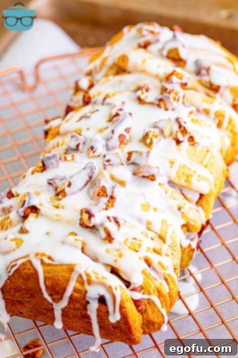 Icing being drizzled over the top of warm Cinnamon Apple Pull-Apart Bread cooling on a cookie rack.