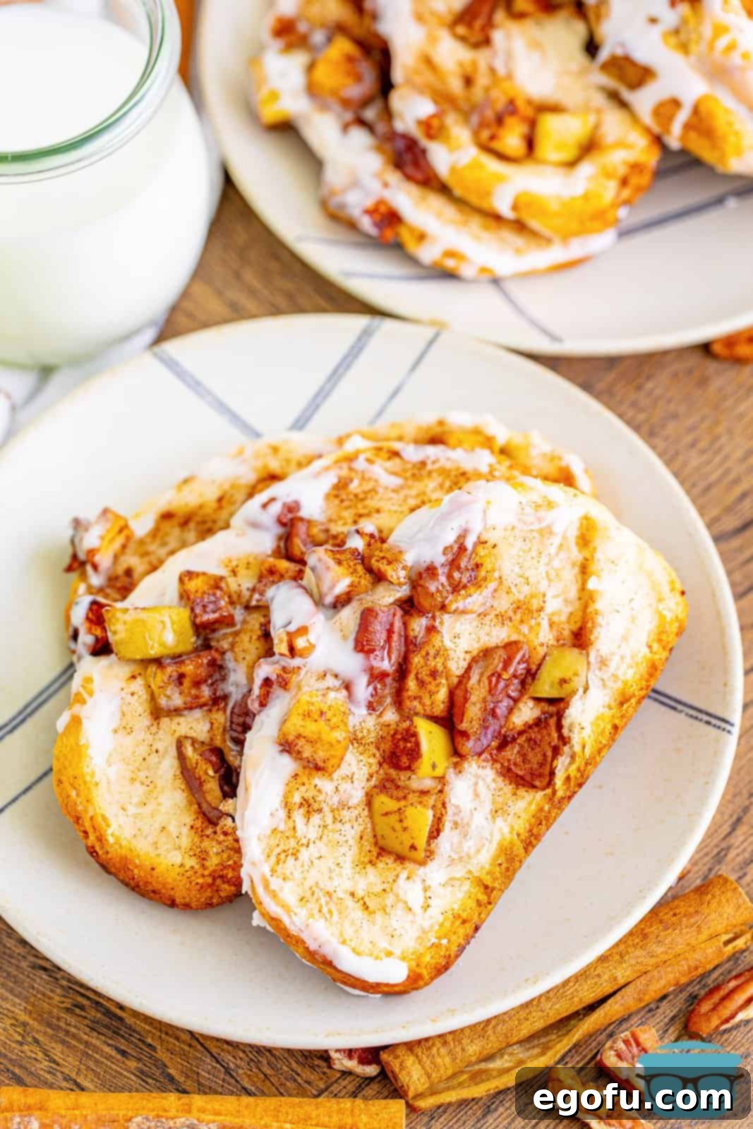 Individual slices of Cinnamon Apple Pull-Apart Bread served on a round white plate, with a glass of milk in the background, ready for a comforting meal.