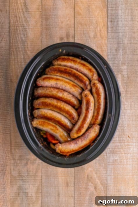Sausage over top peppers and onions in a slow cooker.