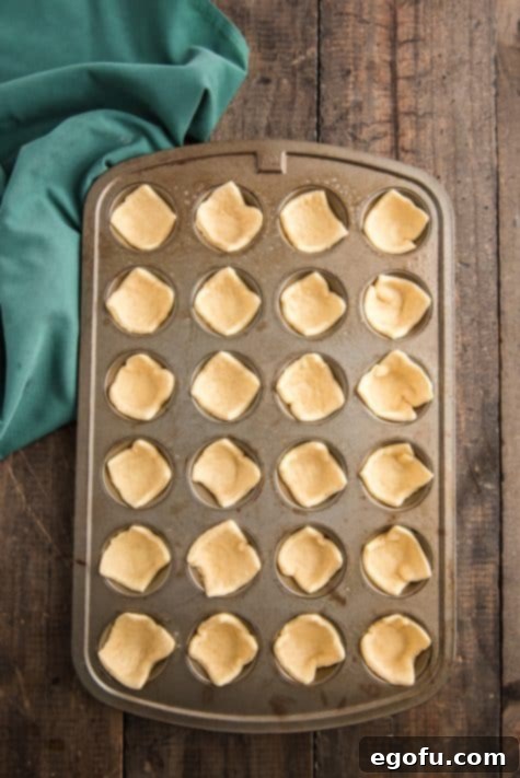 Golden Cranberry Brie Delights 12 crescent dough squares placed into the holes of a mini muffin pan.