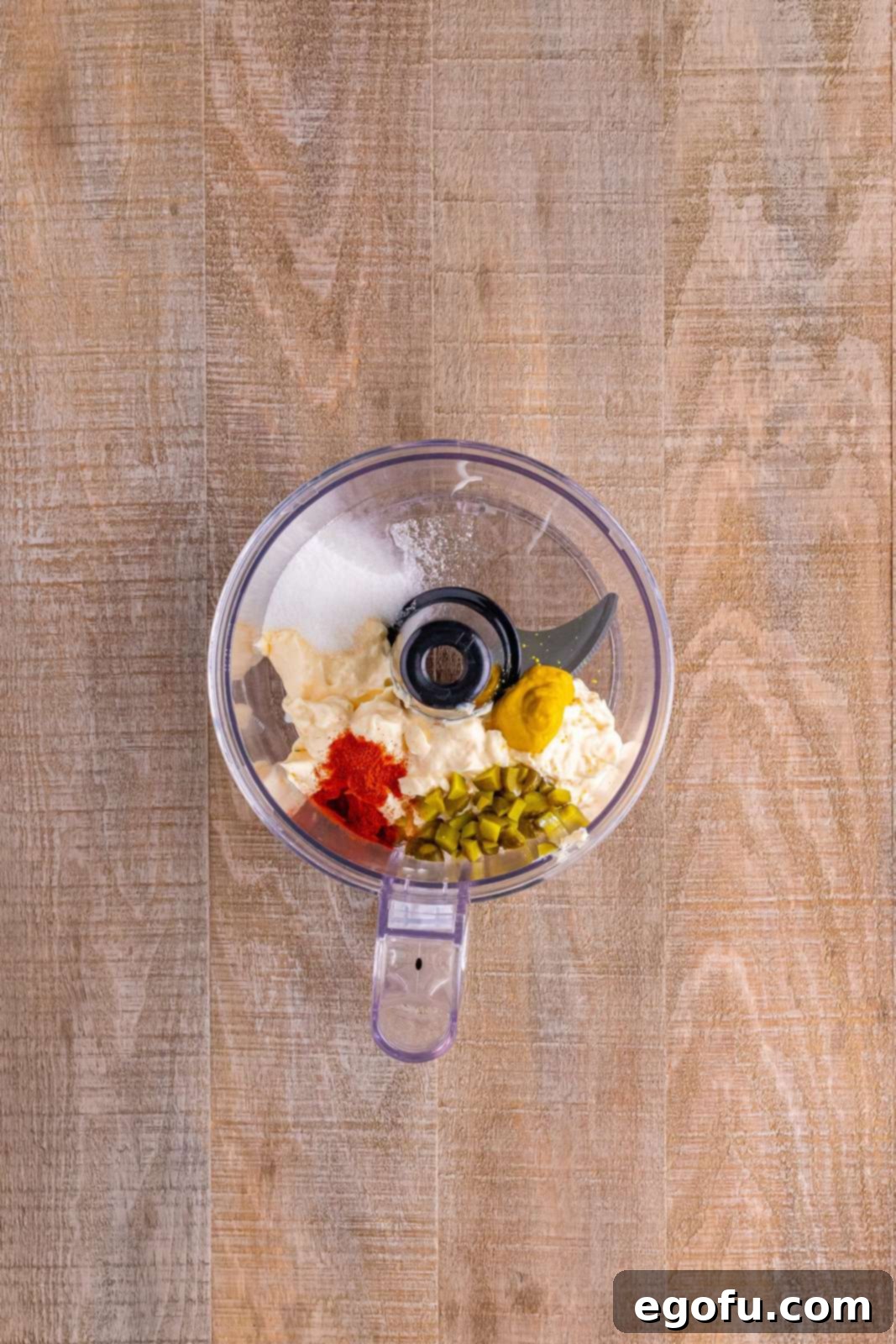 Close-up photo of the Big Mac salad dressing ingredients being blended in a food processor, creating a smooth and creamy sauce. The vibrant colors of the ingredients are visible through the processor's clear bowl.