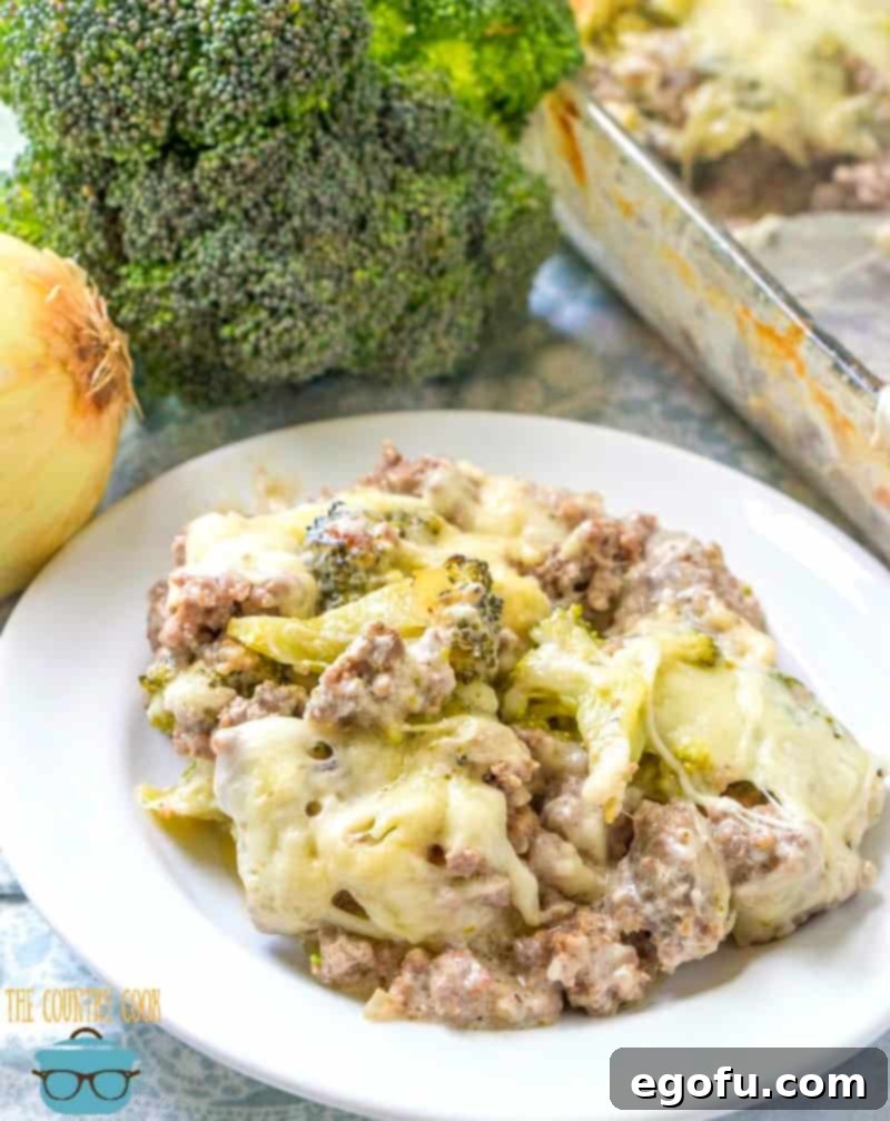 Cheesy Broccoli Hamburger Casserole recipe served on a white plate, showcasing the rich texture and golden-brown cheese.