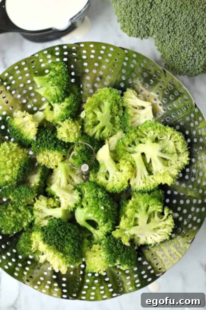 Fresh broccoli florets steaming in a steamer basket, preserving their vibrant green color.