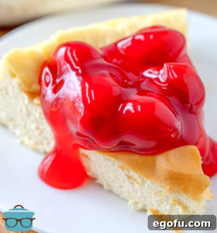 A perfectly sliced low carb cherry cheesecake topped with bright red cherry pie filling on a white plate.