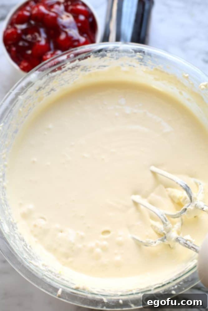 Creamy low carb cheesecake batter in a clear glass mixing bowl.