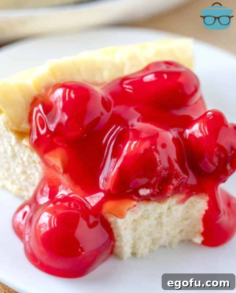 A slice of Low Carb Cheesecake topped with sugar-free cherry pie filling, with a bite taken out, showing its creamy texture.