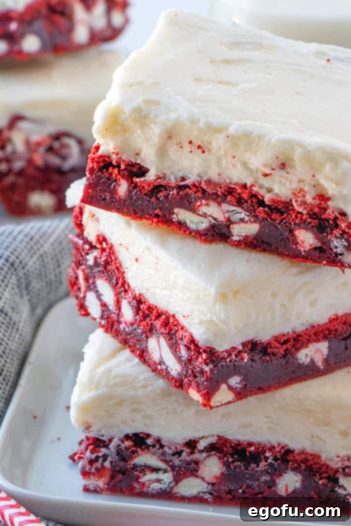 Velvet Red Dream Bars 2 closeup photo of red velvet white chocolate chip bars stacked on a white square plate.
