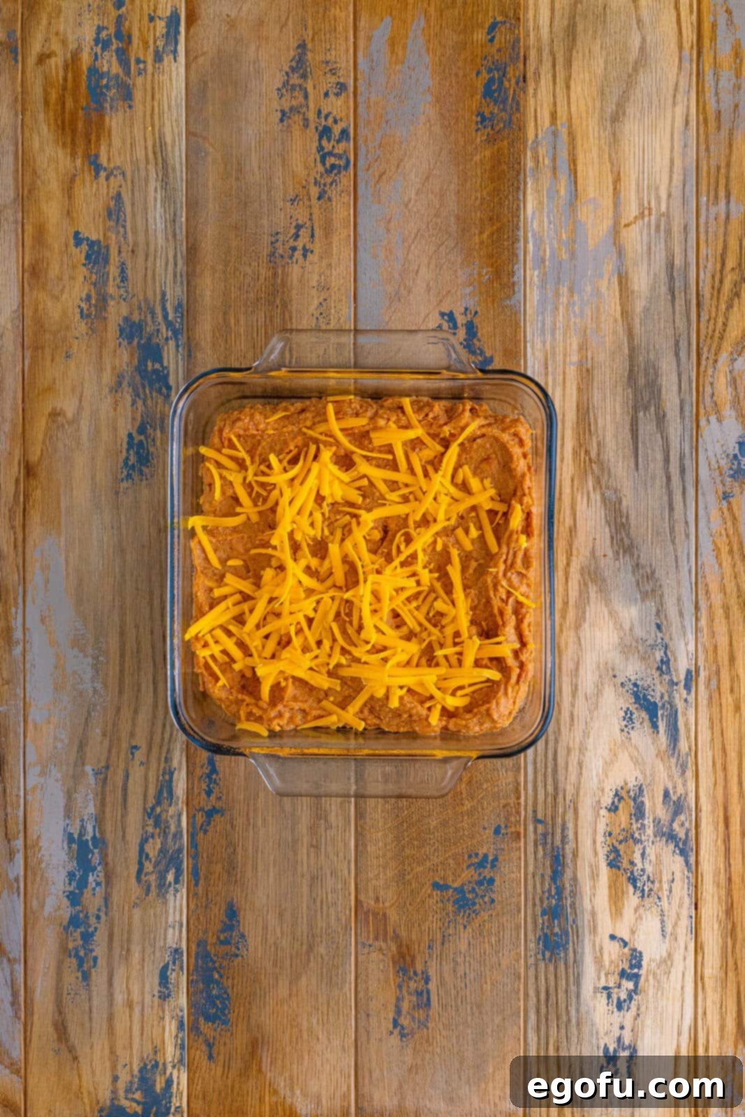 refried bean mixture spread into a baking dish and topped with shredded cheese. 