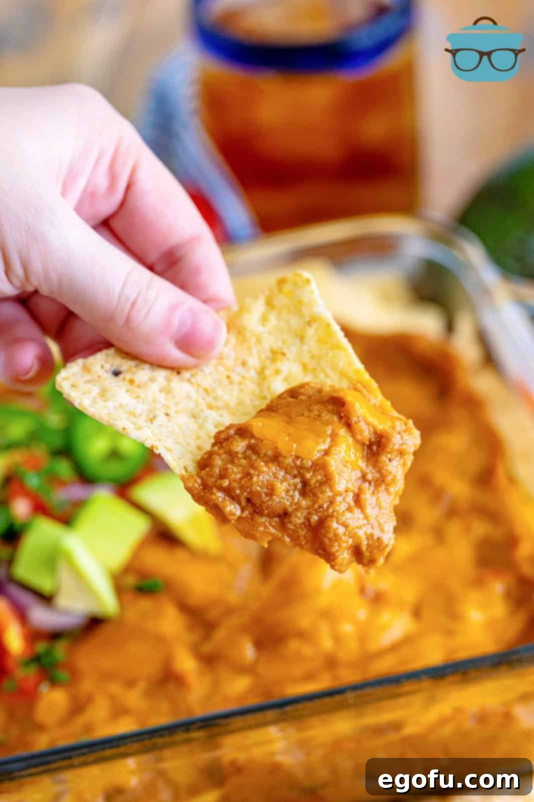 a tortilla chip holding some refried bean dip on the end. 