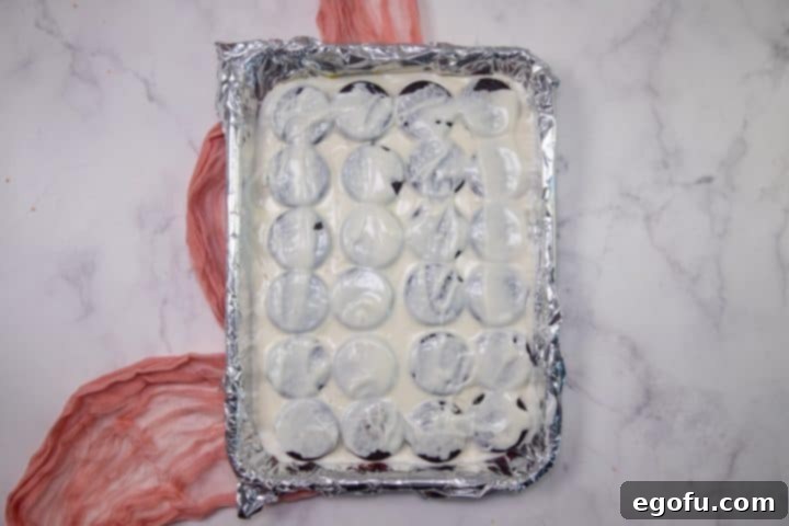 Cupids Oreo Bark 8 meltd vanilla chocolate spread evenly on top of Oreo cookies.