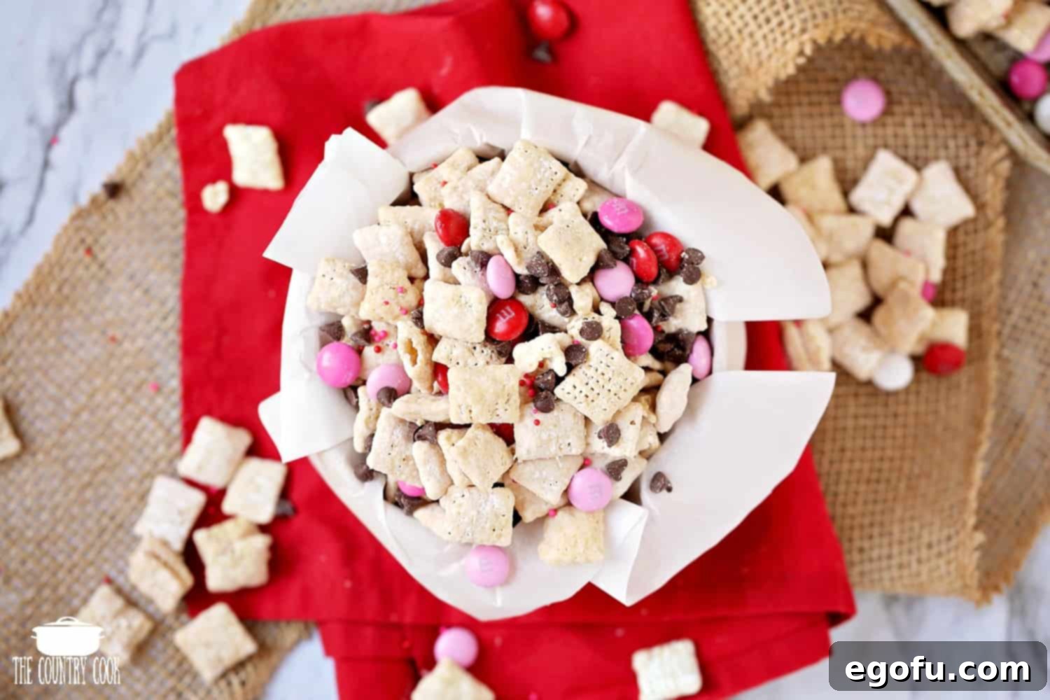 Valentine's Day Muddy Buddy Chex Mix in a bowl with parchment paper.
