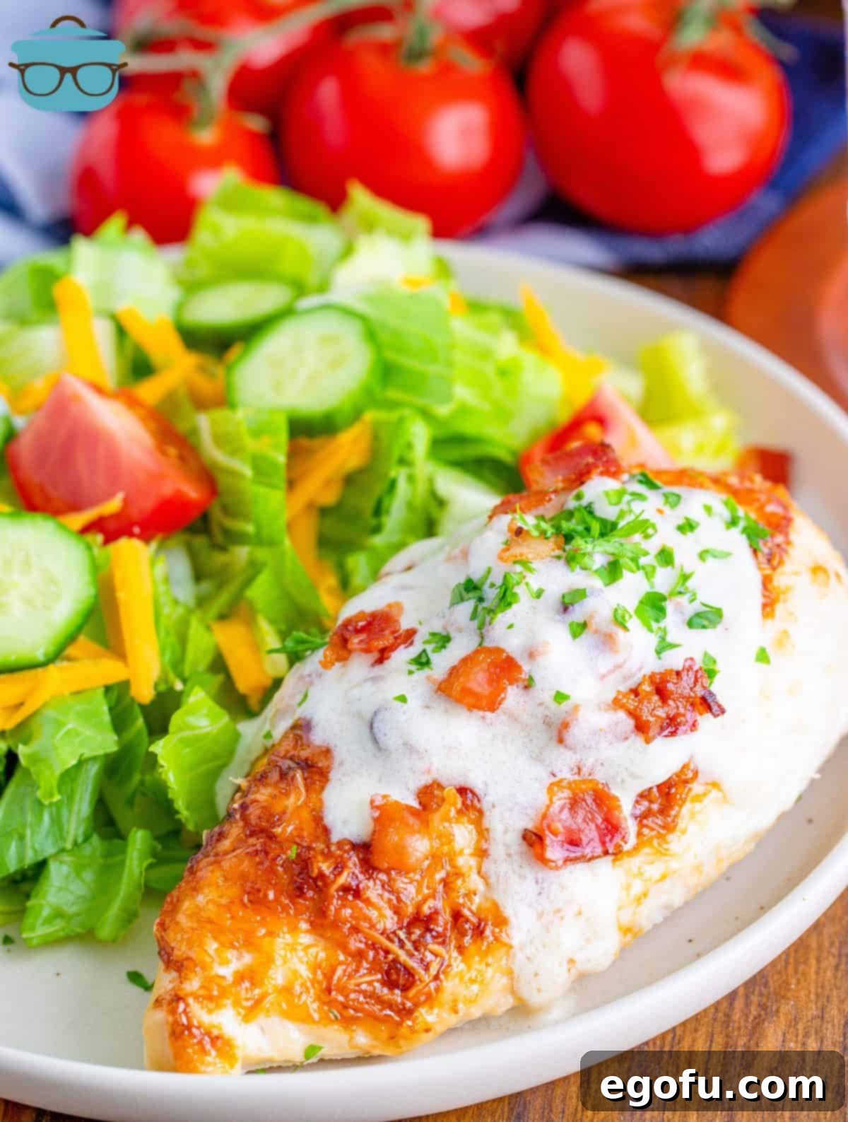 A golden-brown chicken breast on a plate, generously drizzled with rich, creamy bacon sauce, accompanied by a fresh green salad.