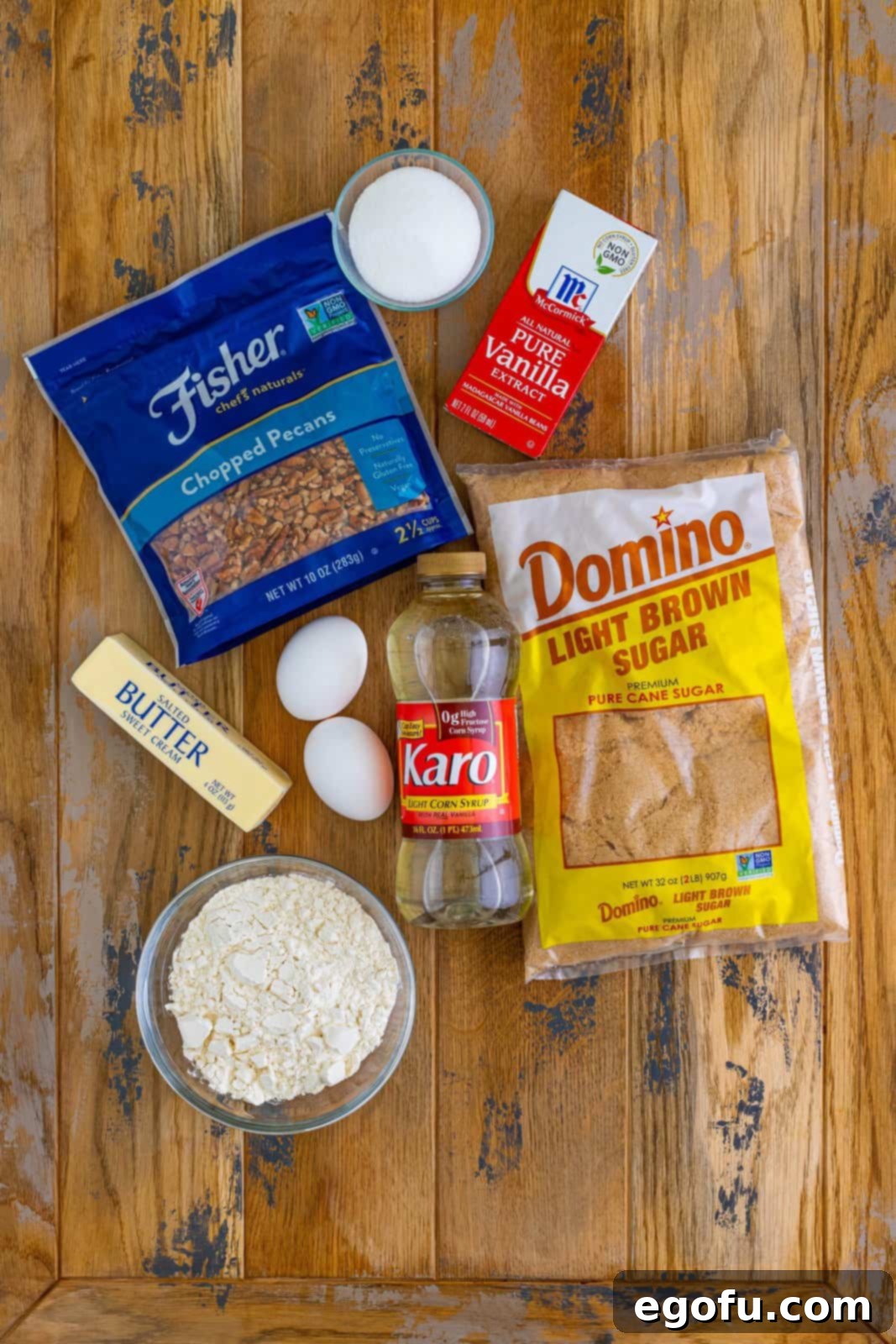 A vibrant flat lay of all the raw ingredients for Southern Pecan Pie Bars: fresh chopped pecans, sticks of salted butter, light brown sugar, vanilla extract, all-purpose flour, light corn syrup, and fresh eggs, ready for baking.