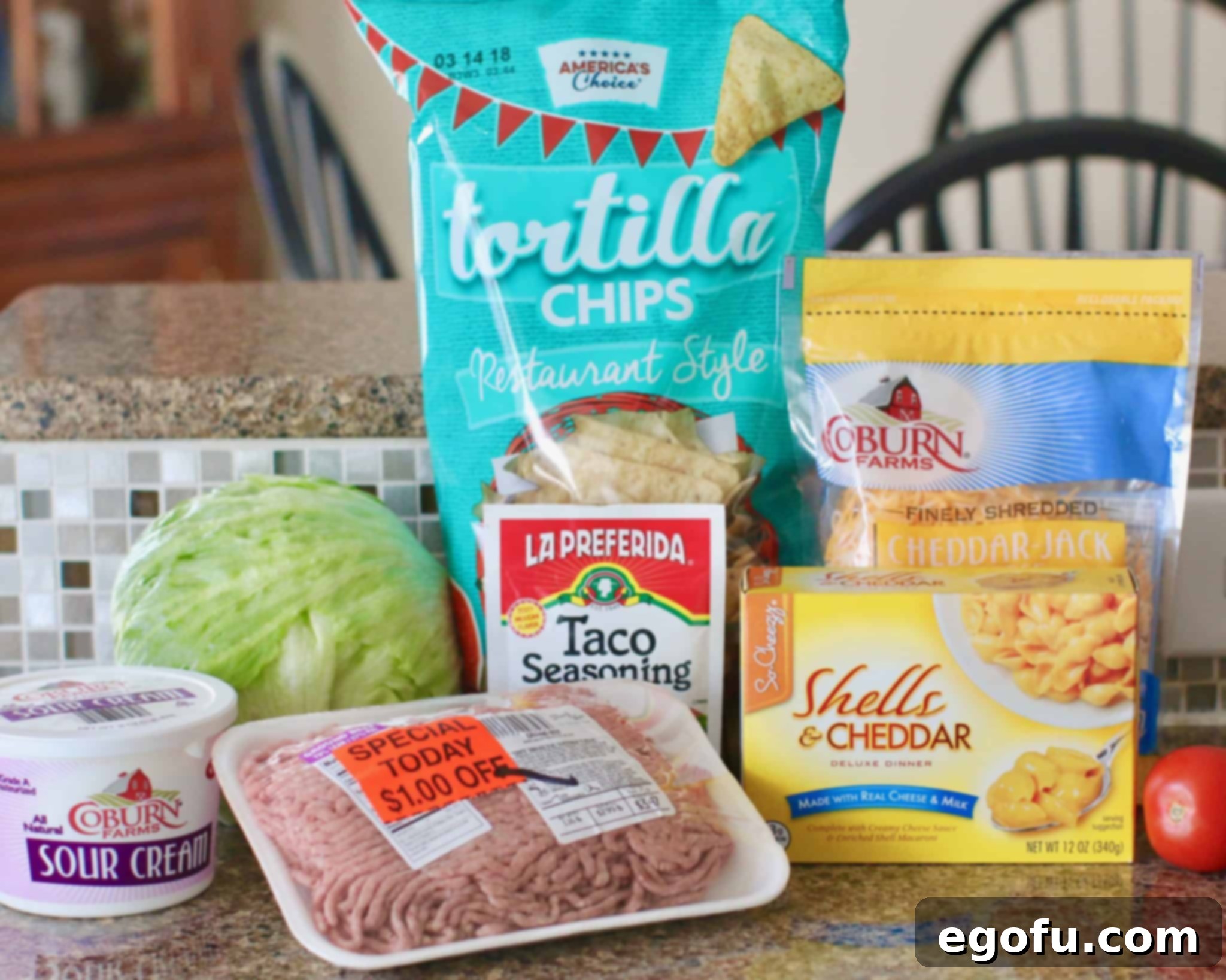 Fiesta Mac and Cheese 4 ground beef, packet taco seasoning, boxed macaroni and cheese, lettuce, tomato, sour cream, tortilla chips, shredded cheddar jack cheese.