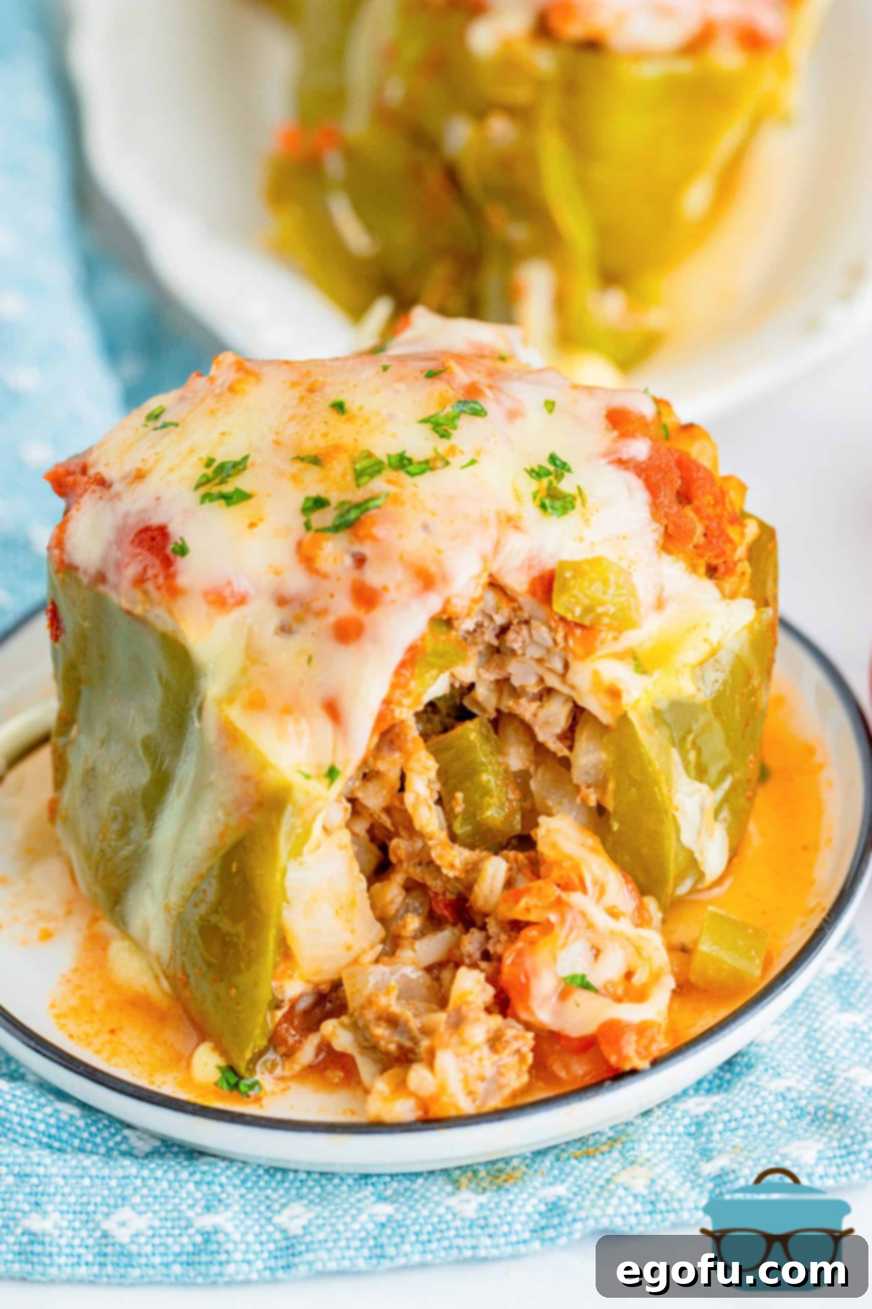 A stuffed pepper shown on a small round plate with a small chunk taken out.