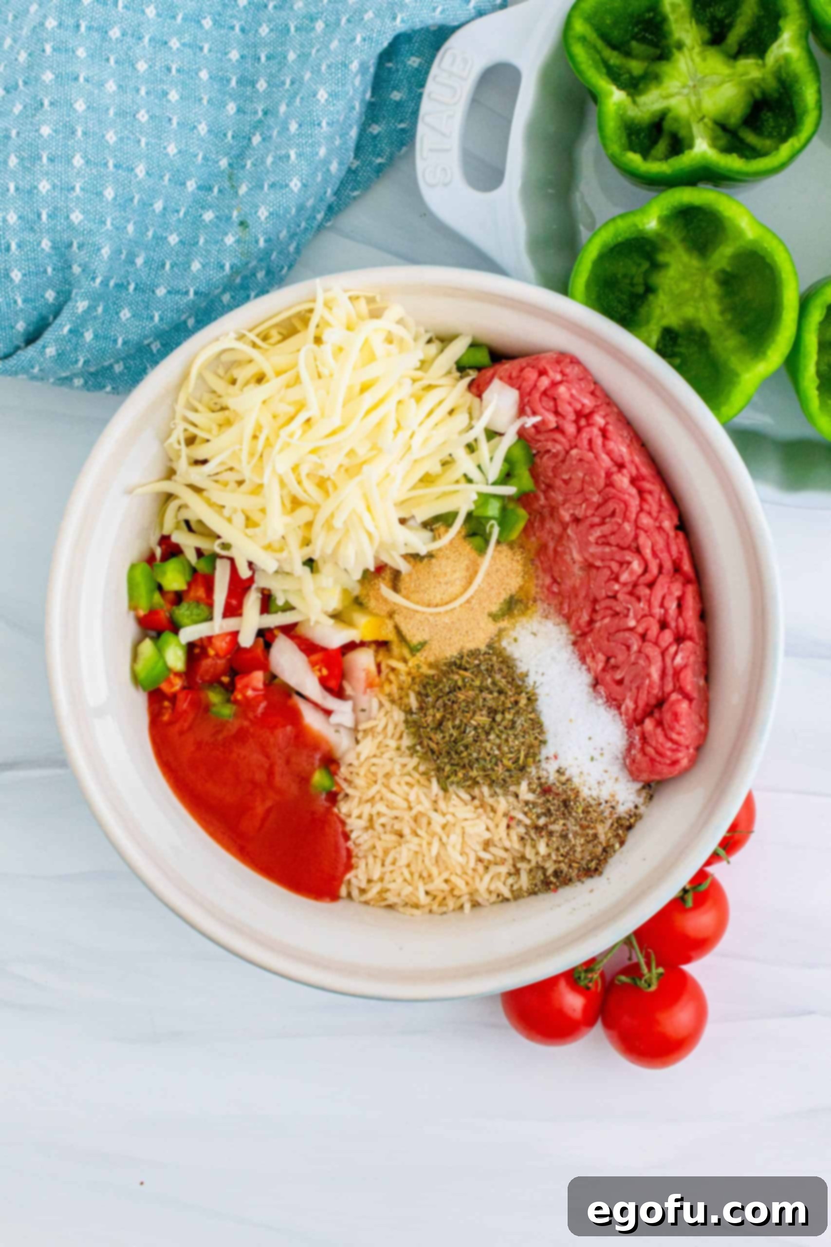 ground beef, instant rice, shredded cheese, tomato sauce, diced green peppers and seasoning in a white bowl.