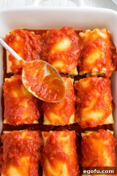 spooning marinara sauce over lasagna rolls.