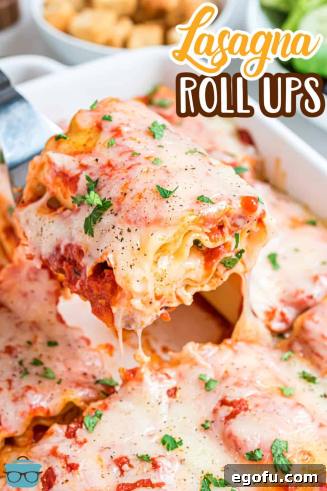 A spatula gently scoops a perfectly baked lasagna roll up from a baking dish, showcasing its golden-brown melted cheese and saucy goodness.