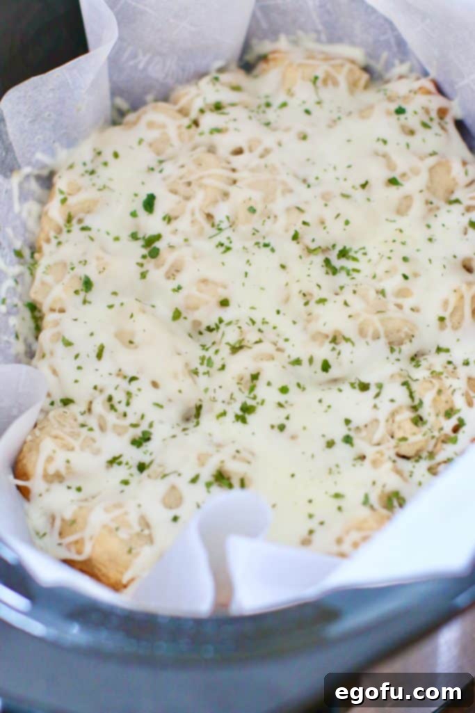 Melted mozzarella cheese creating a gooey, irresistible layer on top of the biscuits in the slow cooker.