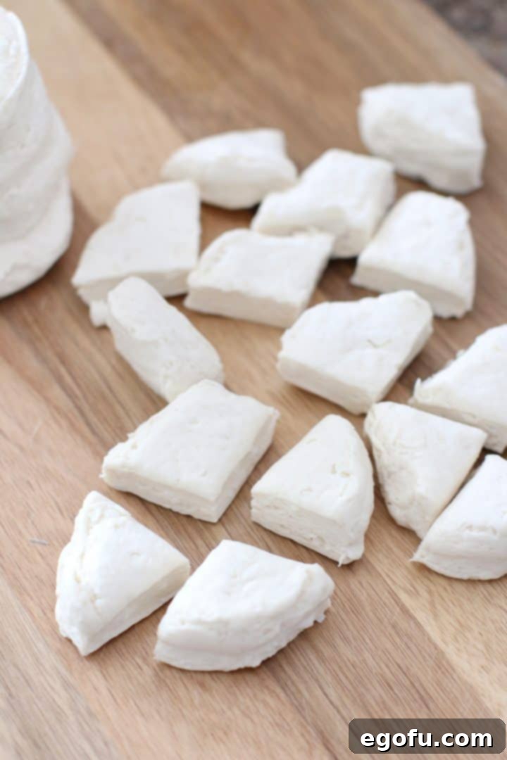 Refrigerated biscuit dough being cut into four equal sections on a white cutting board.