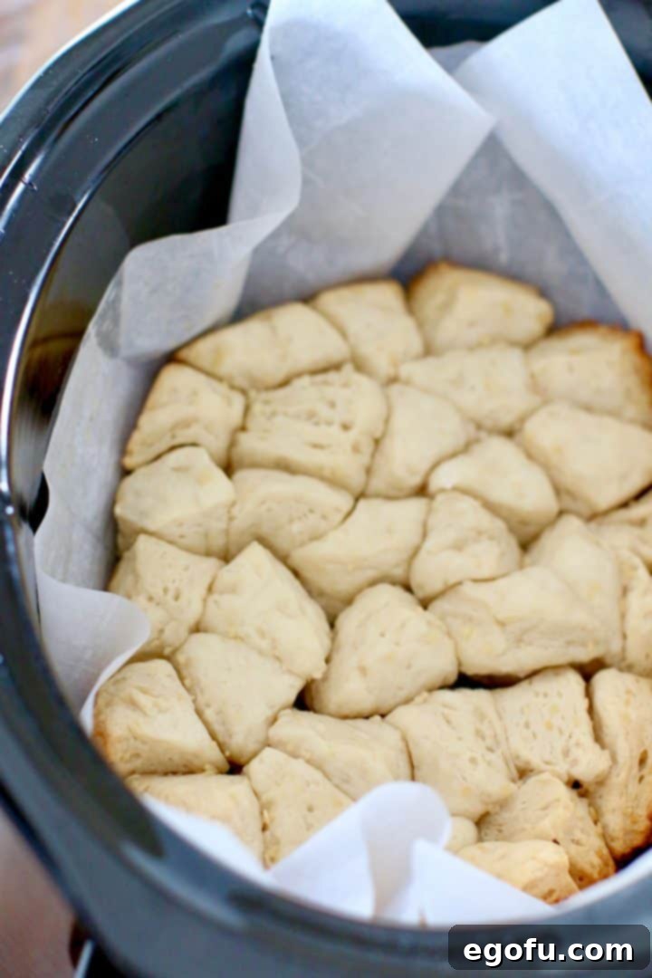 Fully baked and risen biscuits inside a slow cooker, appearing soft and white.