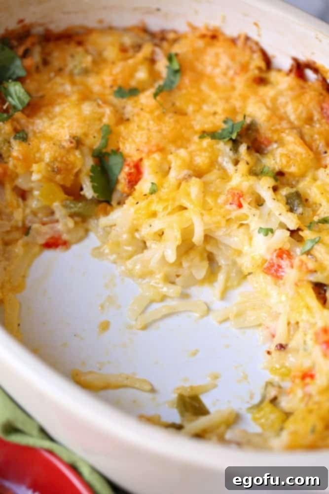 Lone Star Morning Spud Bake 7 A fully baked Tex-Mex hash brown casserole in an oval white baking dish, golden brown and bubbling with melted cheese on top, fresh out of the oven and ready to be served.