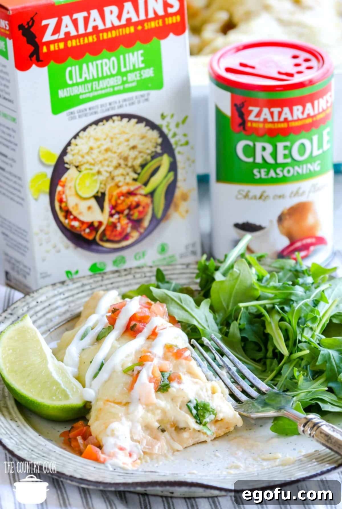 Easy Creamy Shrimp Enchiladas with Zatarain's Cilantro Lime Rice and Creole Seasoning packaging being shown in the background.