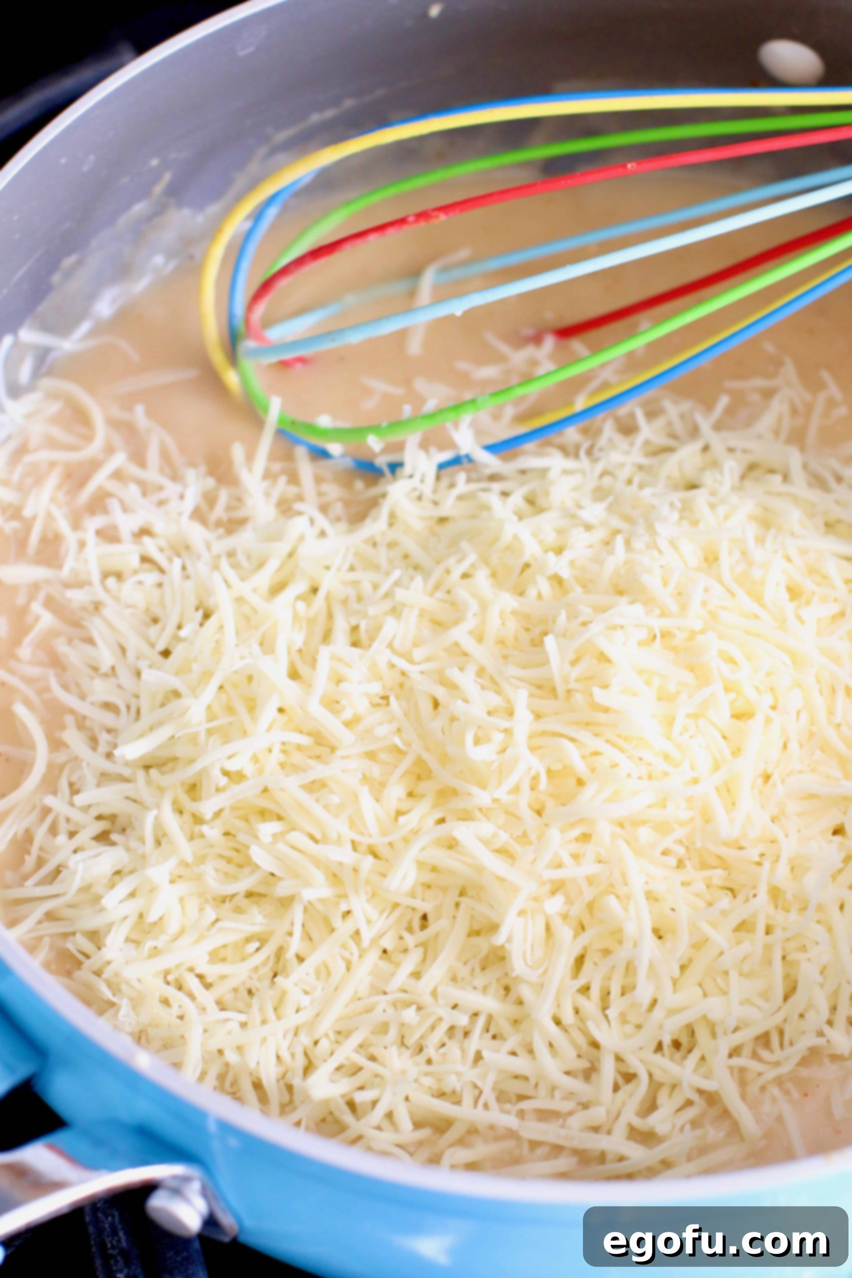 shredded Monterey Jack stirred into cream mixture with a whisk in a skillet.